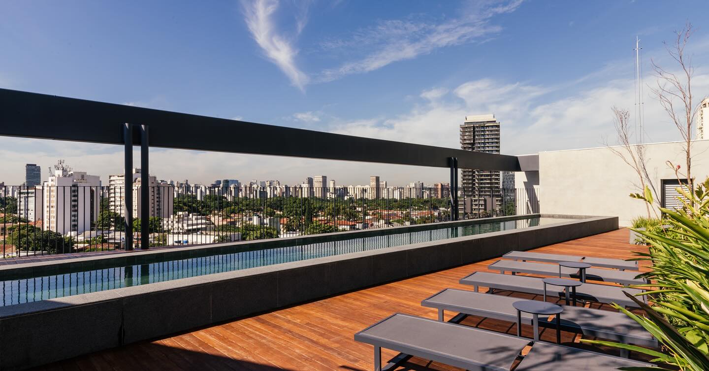 Área de Lazer do ESQUINA Pinheiros – Piscina com vista para o skyline Piscina com deck e vista panorâmica do ESQUINA Pinheiros, empreendimento de alto padrão na Rua dos Pinheiros, São Paulo