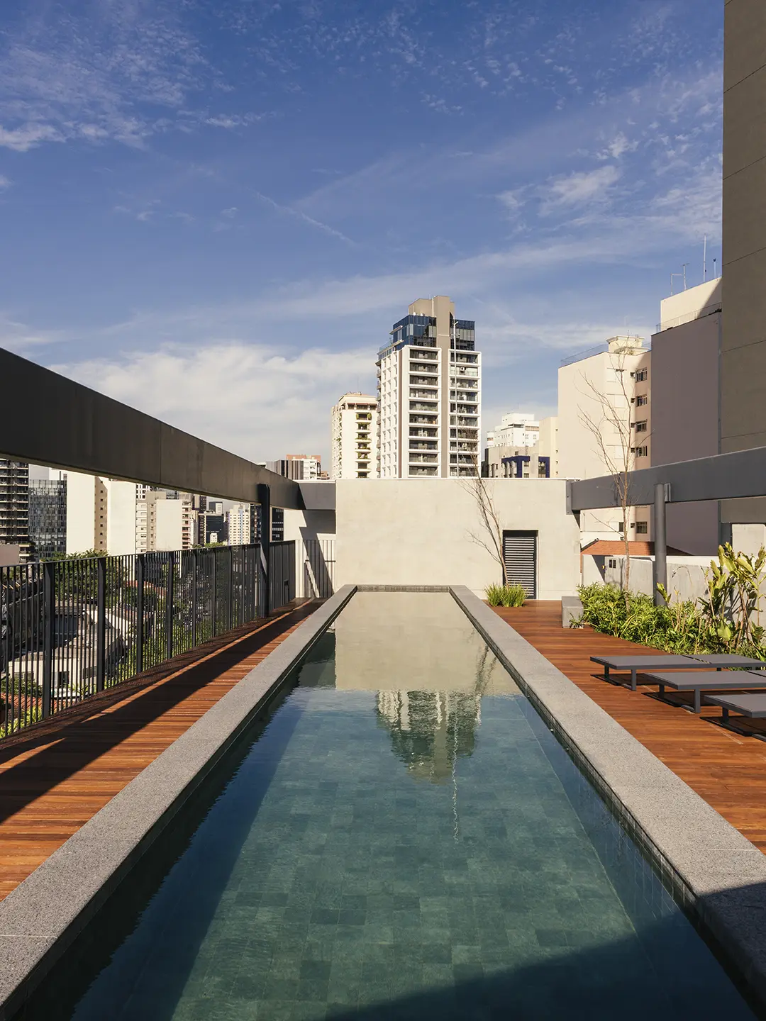Piscina com deck de madeira e solarium do ESQUINA Pinheiros. Foto do empreendimento pronto
